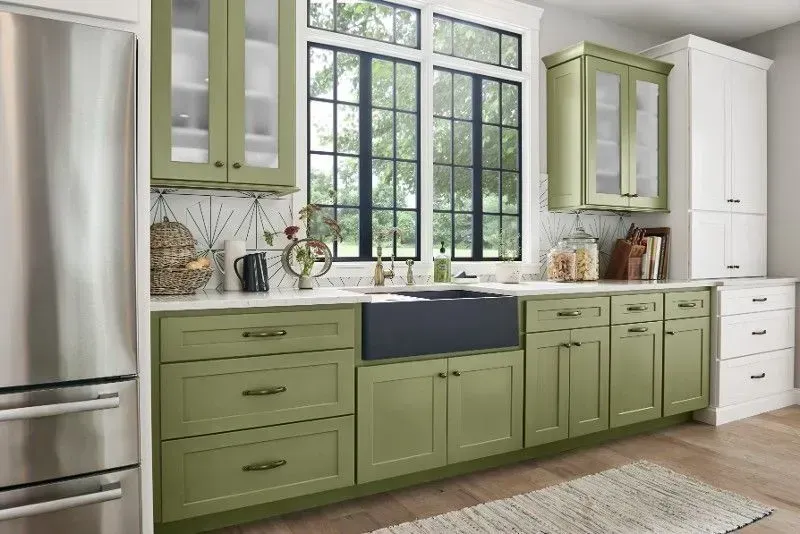 Kitchen with olive green cabinets, a dark farmhouse sink, and large window.