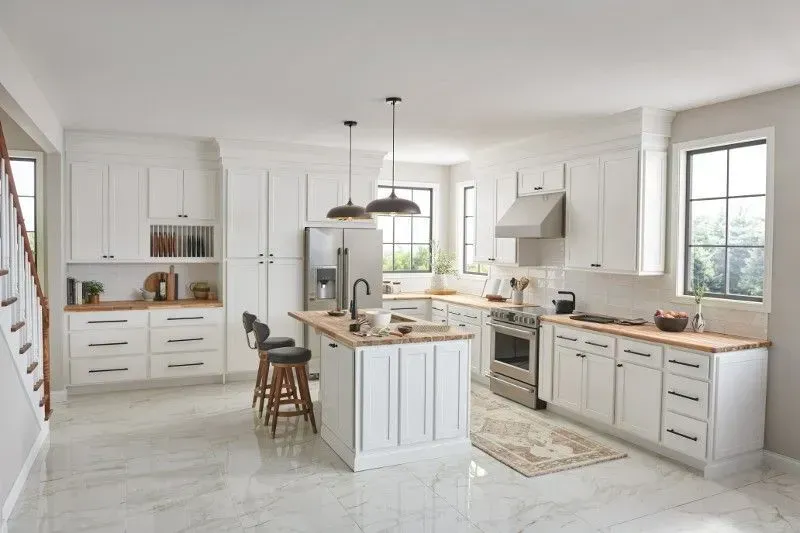 White kitchen with wooden countertops, stainless steel appliances, and island with stools.