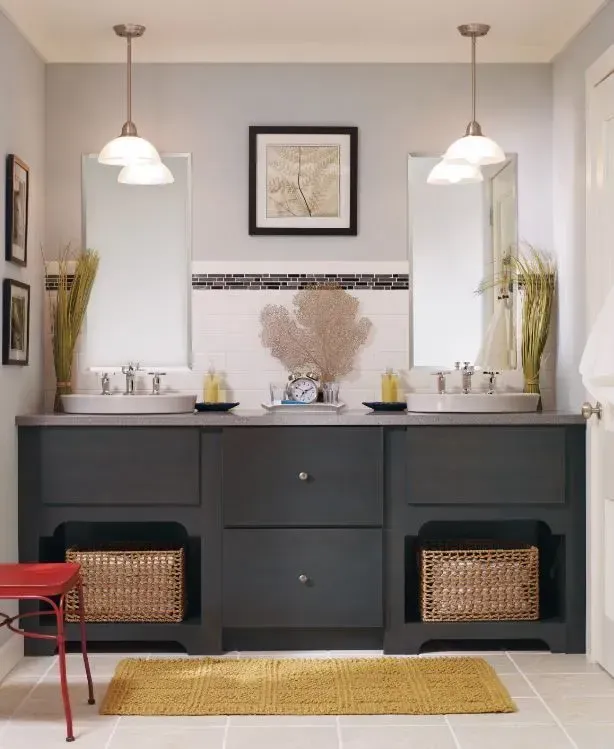 Gray bathroom with a dark cabinet, two sinks, mirrors, and pendant lights. A yellow rug sits on the floor.
