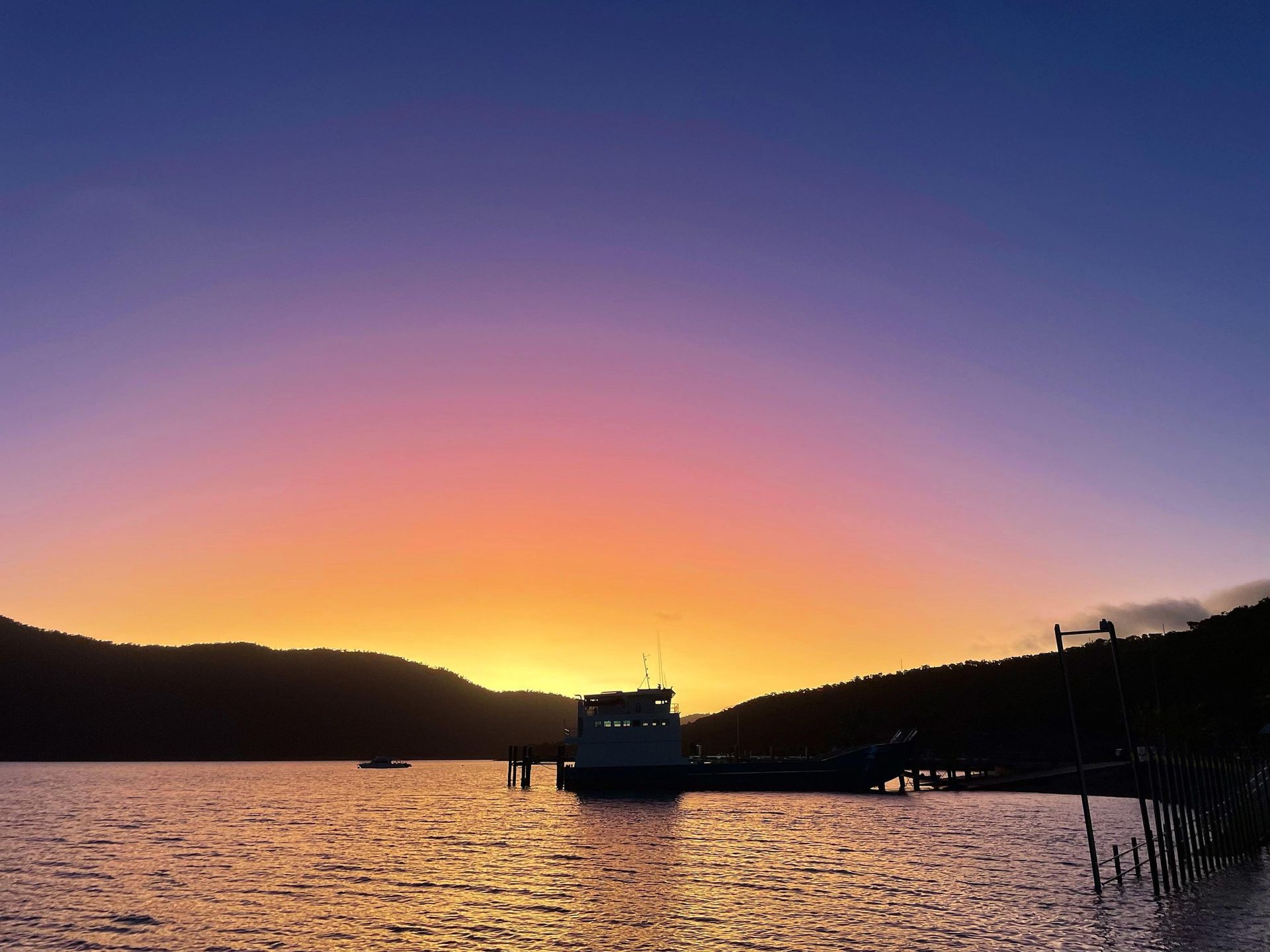A sunset over a body of water with a boat in the distance