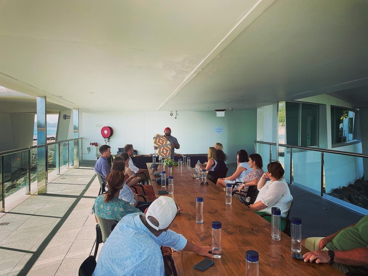 A group of people are sitting around a long wooden table.