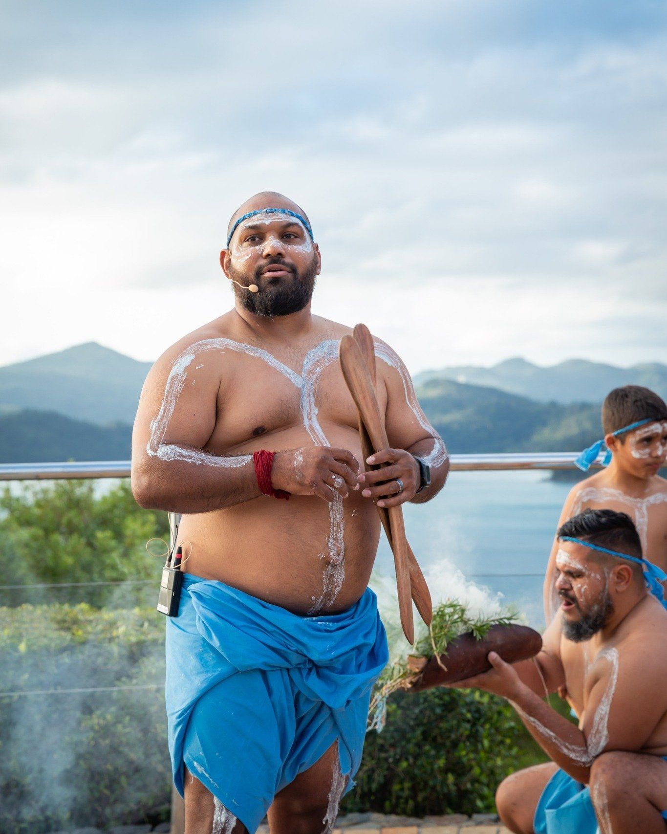 A group of men are standing on a balcony overlooking a body of water.