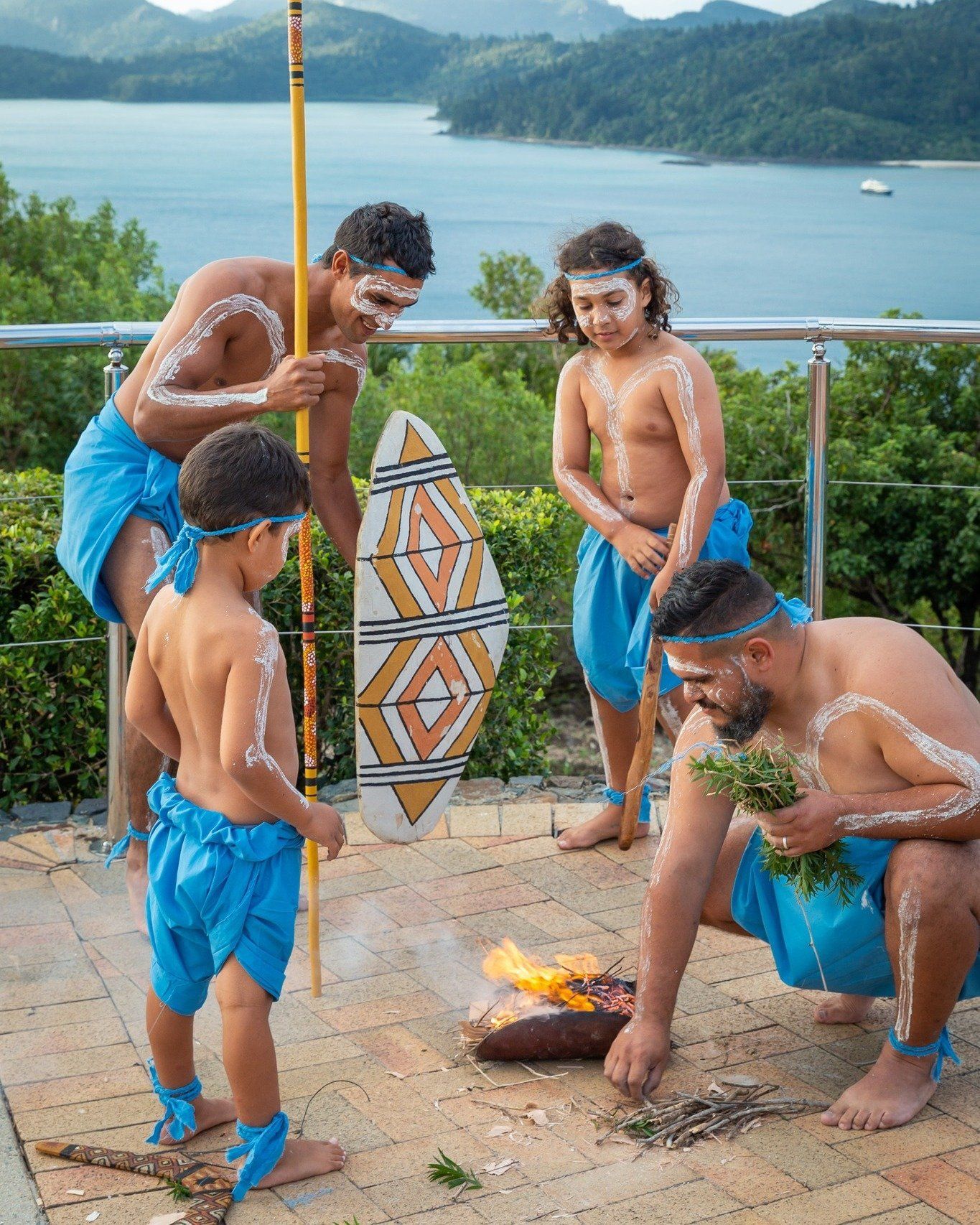 A group of men and children are standing around a fire.