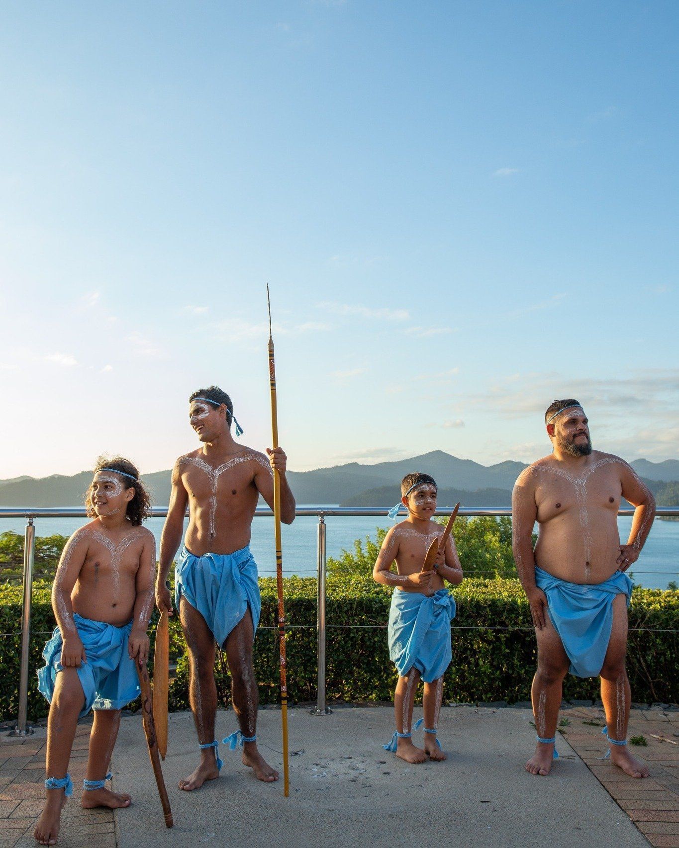 A group of men are standing next to each other in front of a body of water.