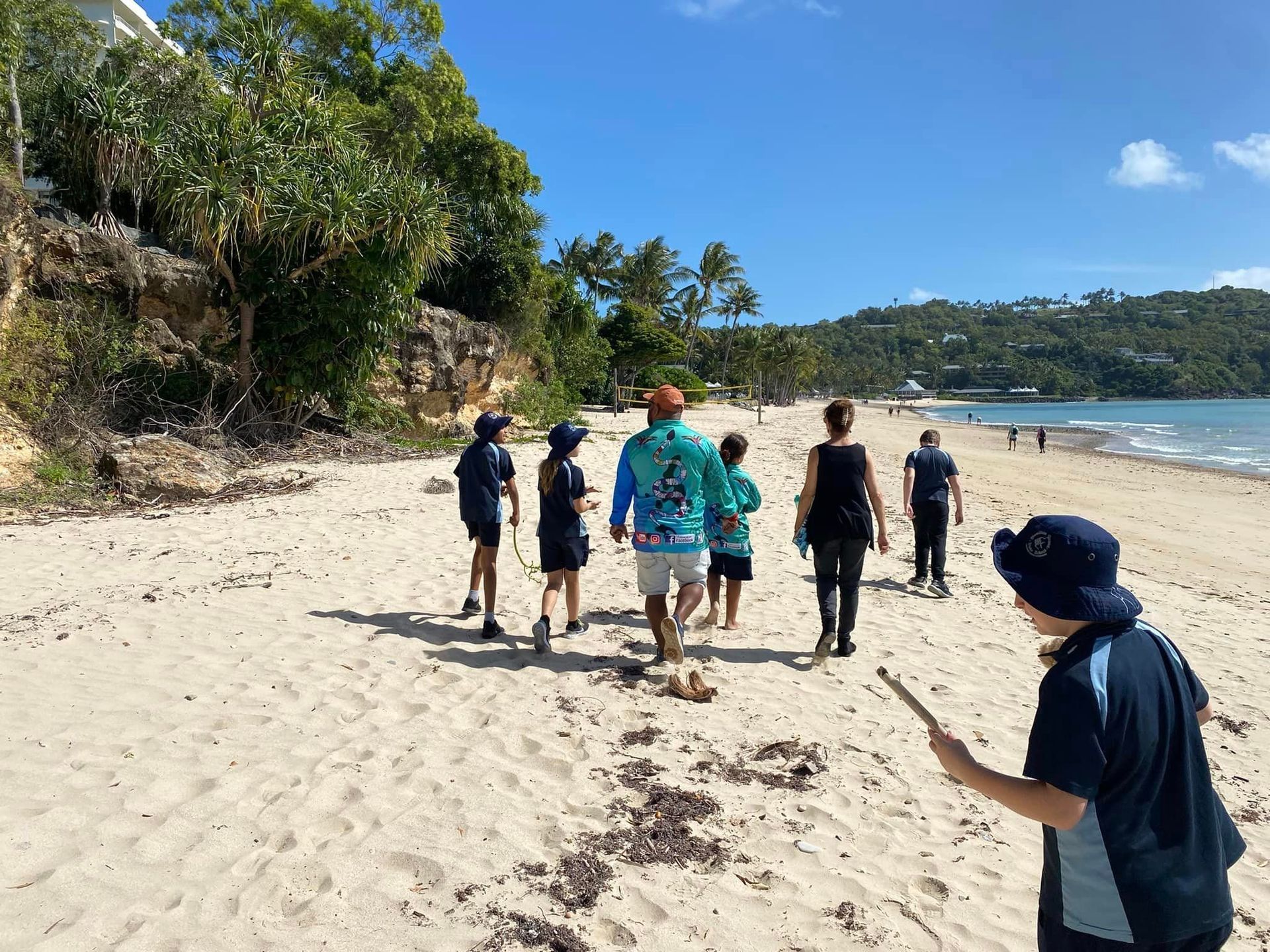 A group of people are walking on a sandy beach.