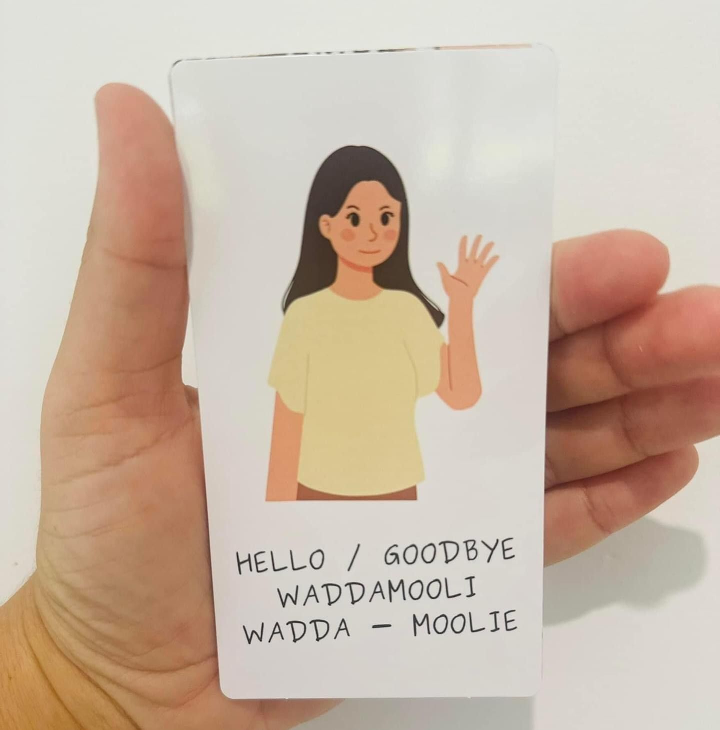 A hand holding a card that says hello goodbye wadda moolie