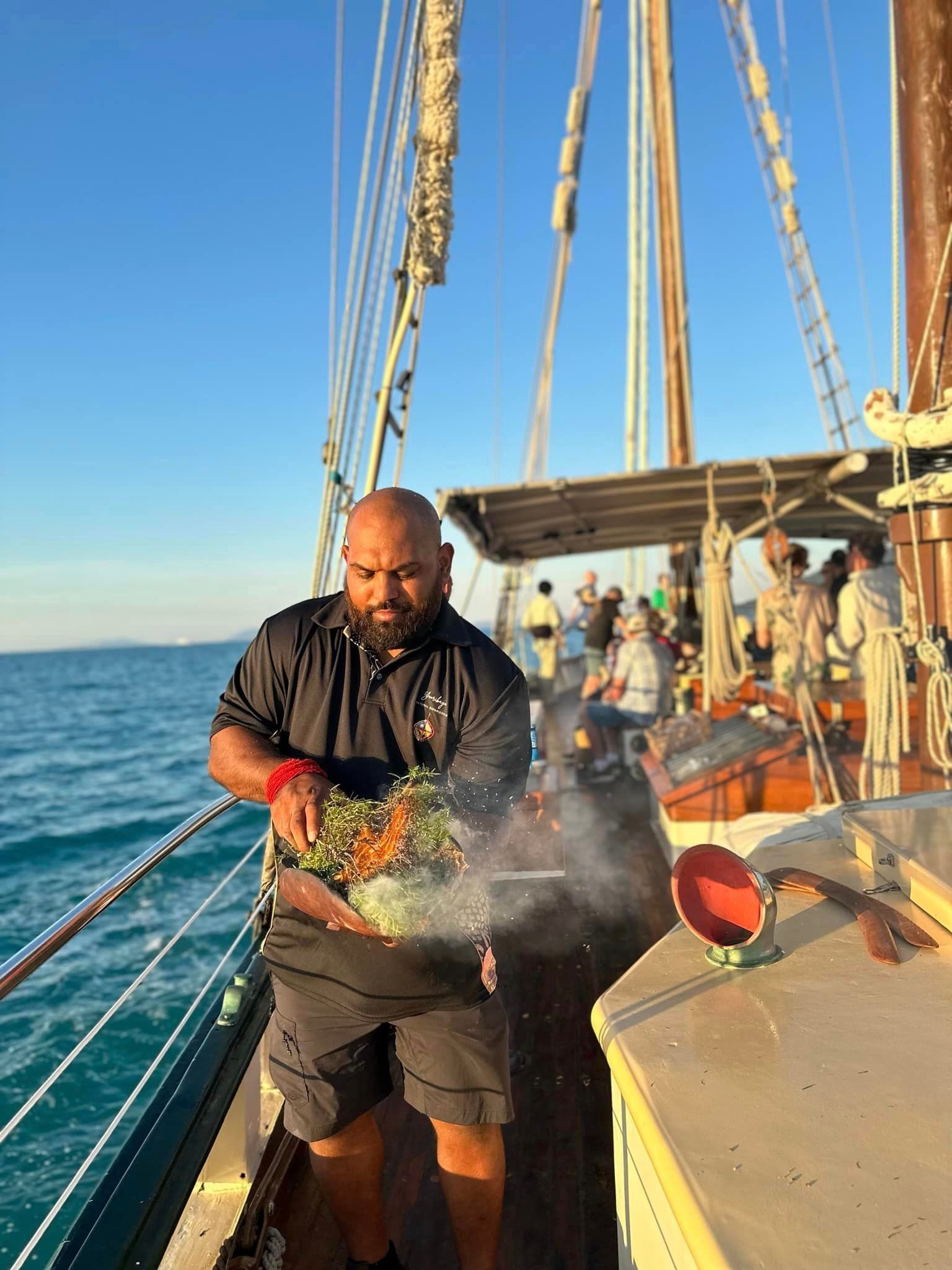A man is cooking food on a boat in the ocean.