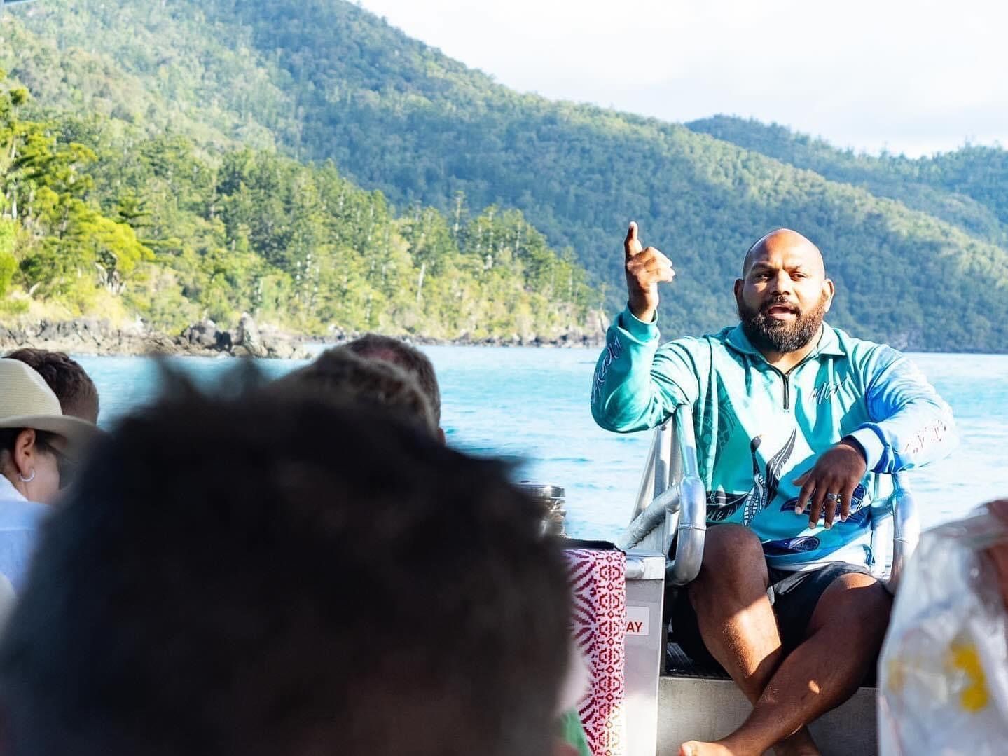 A man is sitting on a boat talking to a group of people.