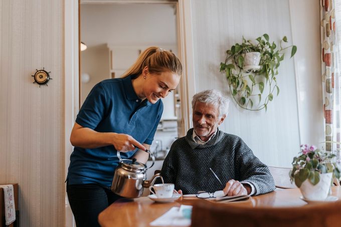 A Woman Is Pouring Tea For An Elderly Man - DeSoto, TX - Amazing Hearts Homecare & Staffing