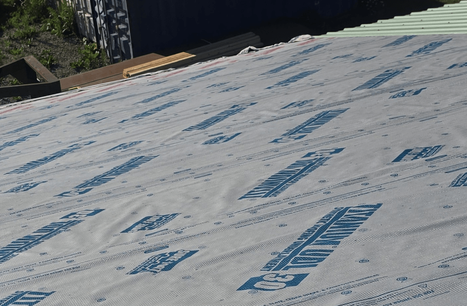 Roll of blue and white roofing underlayment on a rooftop.