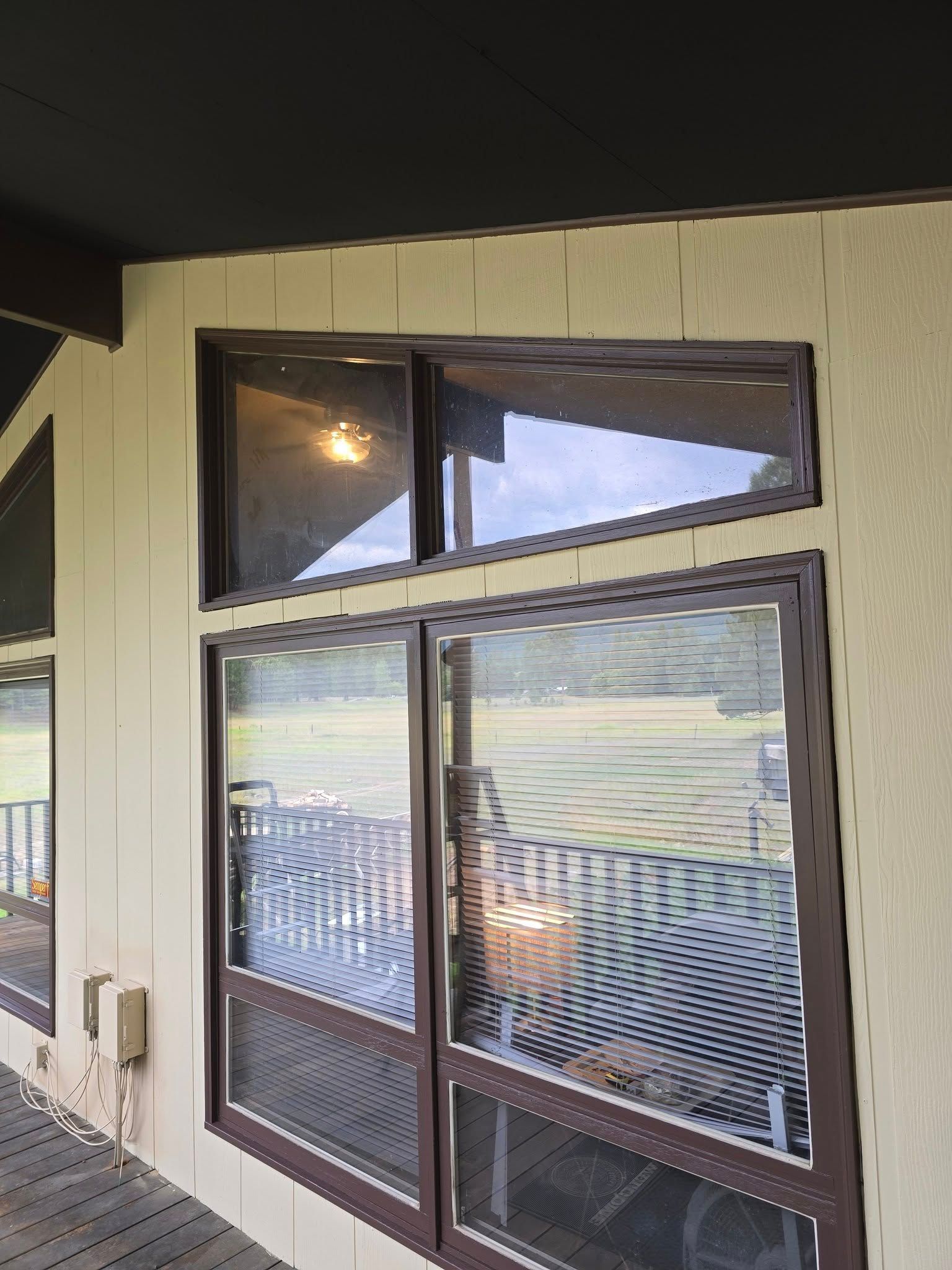 Brown-framed windows on a light-colored building exterior, reflecting outdoor scenery.