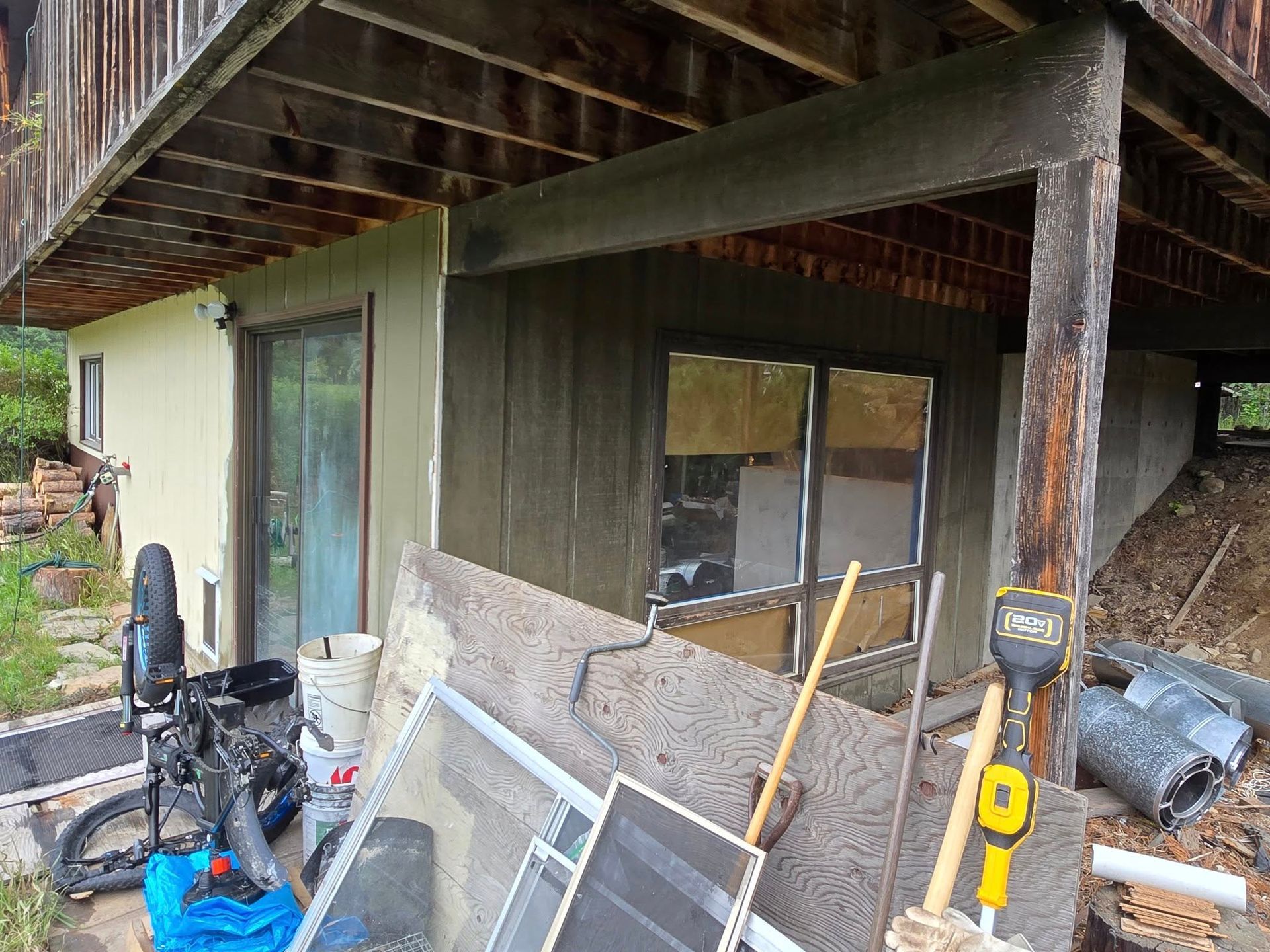 Exterior of a building with debris, windows, a door, and a bicycle parked nearby.
