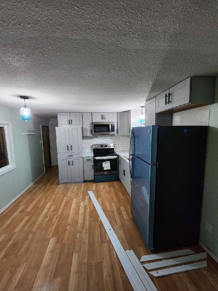 Kitchen with light gray cabinets, black appliances, and wood-look flooring.