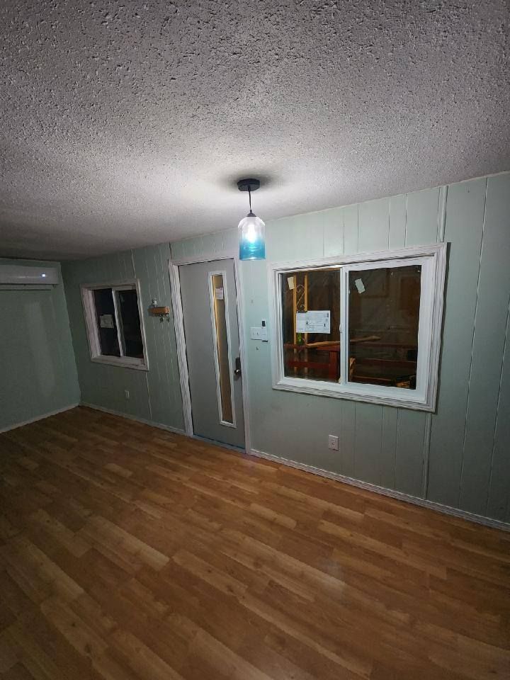 Interior of a room with light green walls, wooden floor, and a blue pendant light.