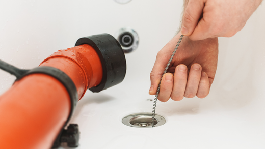 A person is using a chain to remove a drain from a sink.
