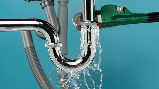 A plumbing pipe with water coming out of it and a wrench.