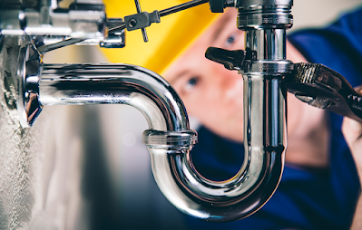 A plumber is fixing a sink pipe with a wrench.