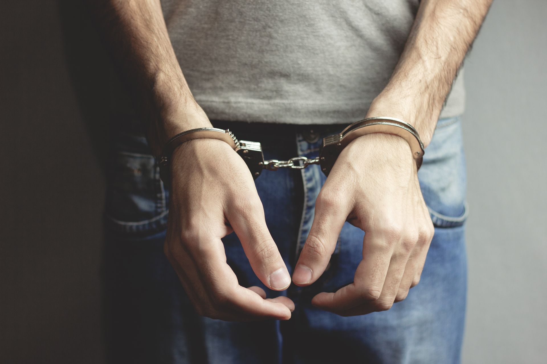 Young man hand handcuffs on dark background. Young man hand handcuffs on dark background.