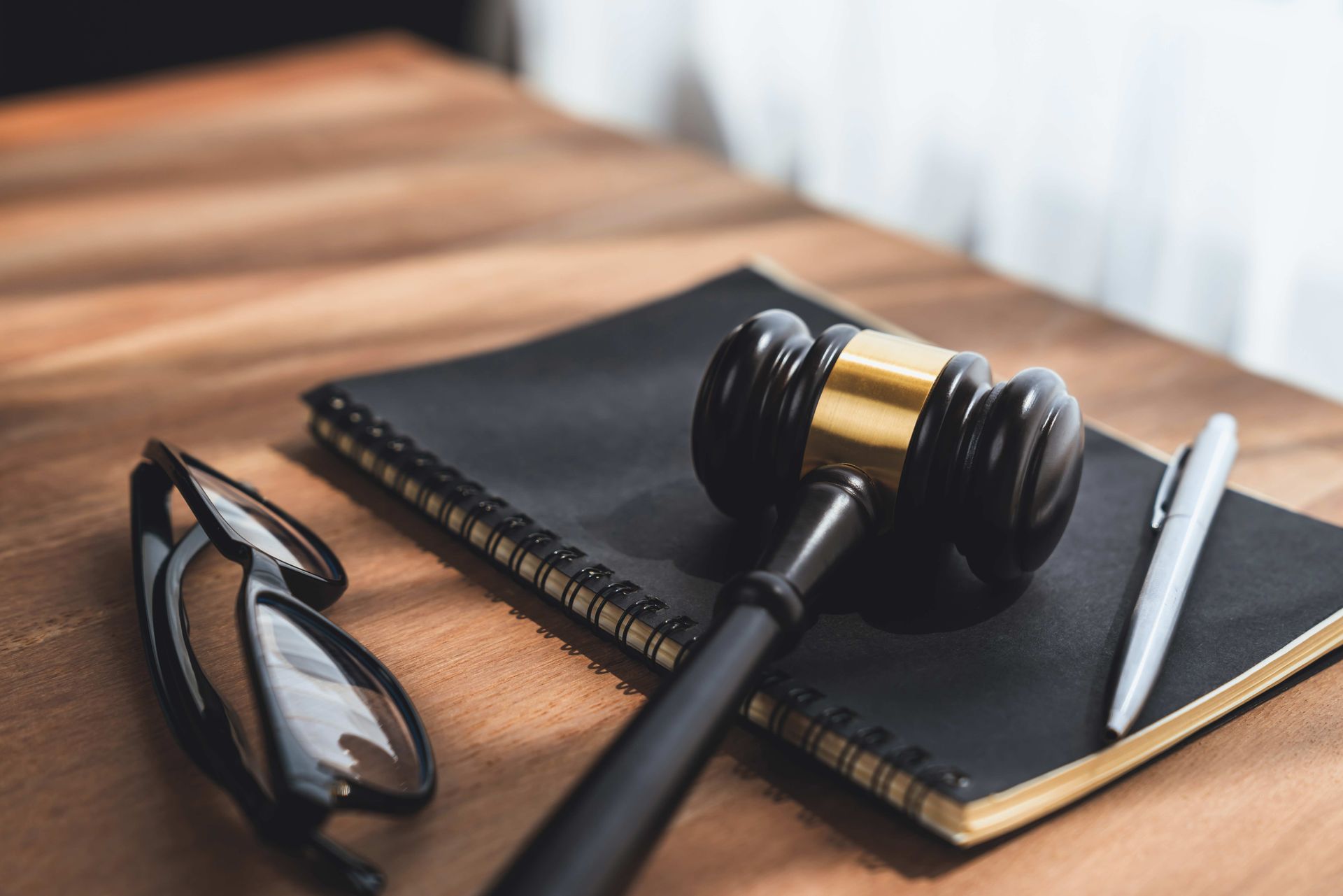 Judge's gavel, law books, glasses, and pens on wooden desk symbolizing justice and legal authority. Judge's gavel, law books, glasses, and pens on wooden desk symbolizing justice and legal authority.