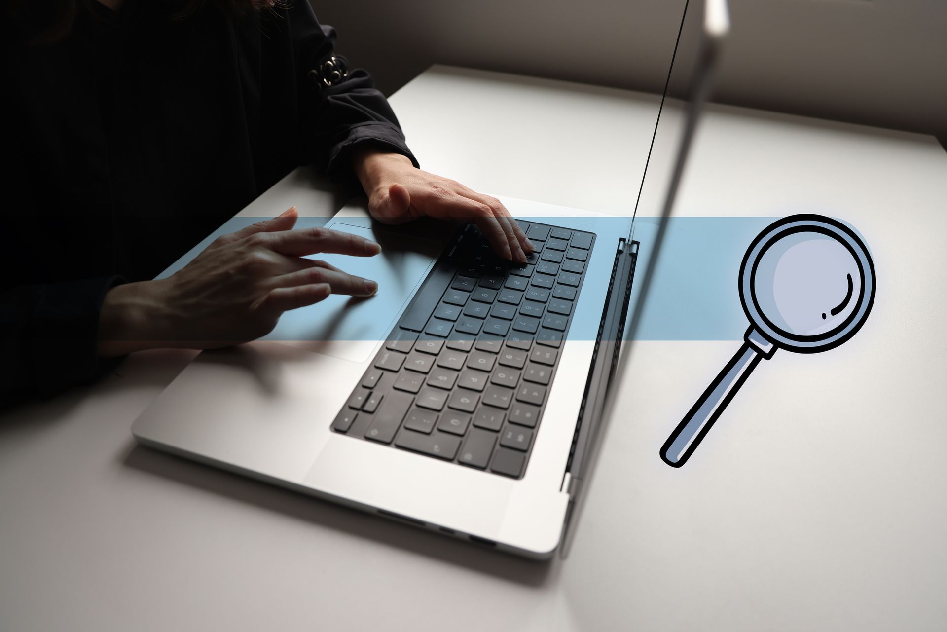 Close-up of a person performing an inmate research on a laptop, and a magnifying glass.