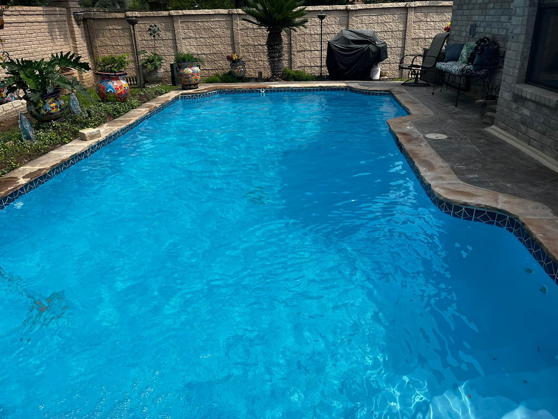 There is a large swimming pool in the backyard of a house.