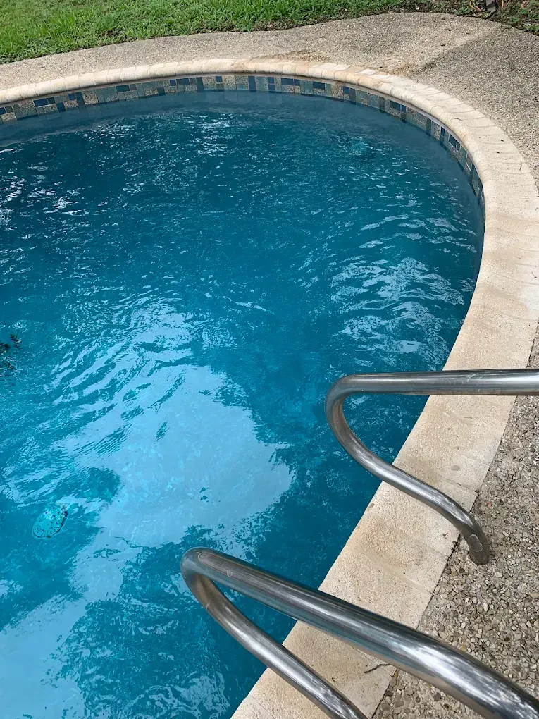 A swimming pool with blue water and stairs leading to it.
