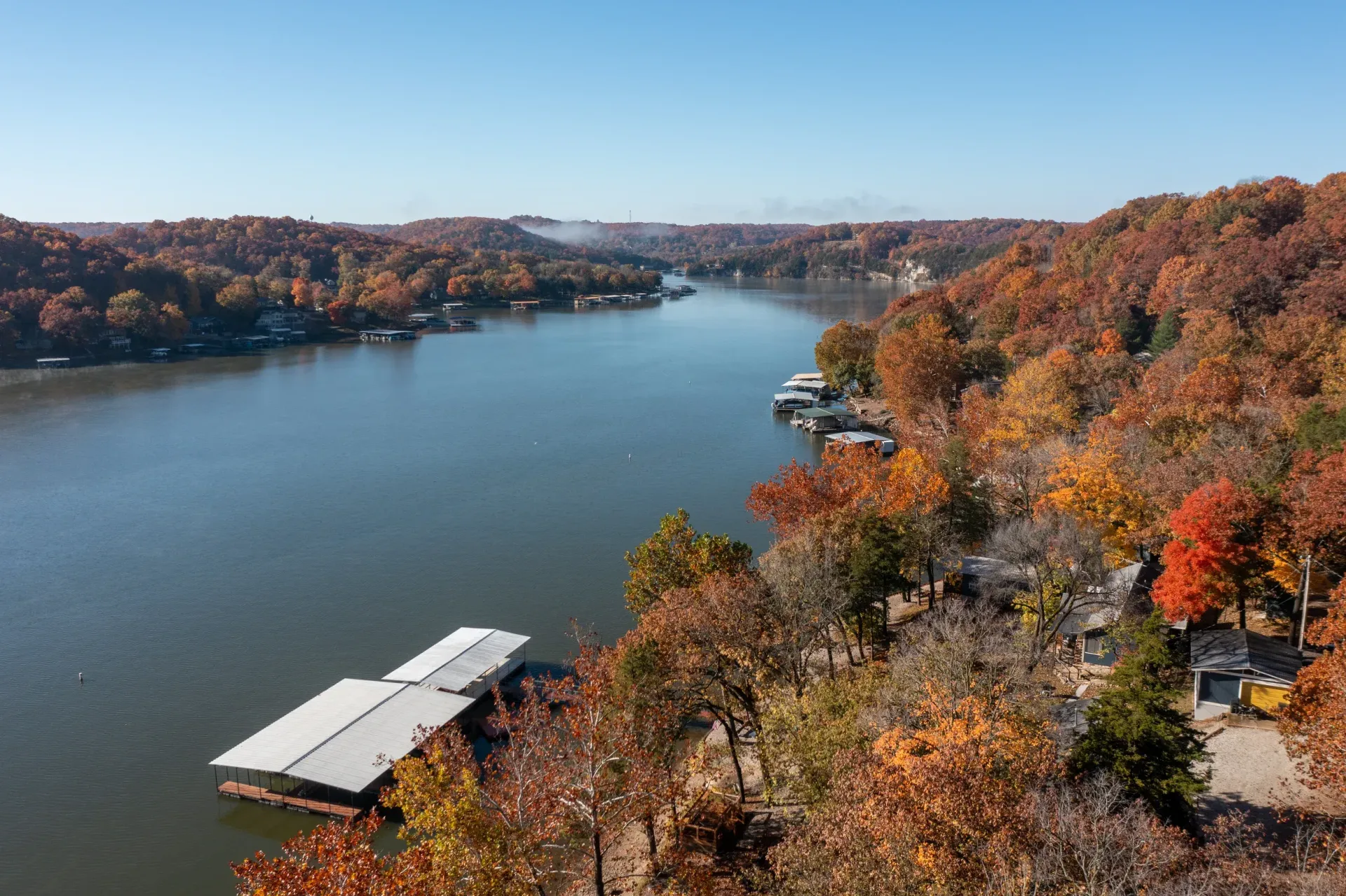 An aerial view of a lake surrounded by trees on a sunny day.