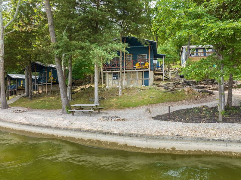 A group of cabins are sitting next to a lake surrounded by trees.