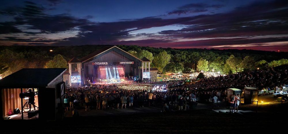 A large crowd of people are gathered in front of a stage at night