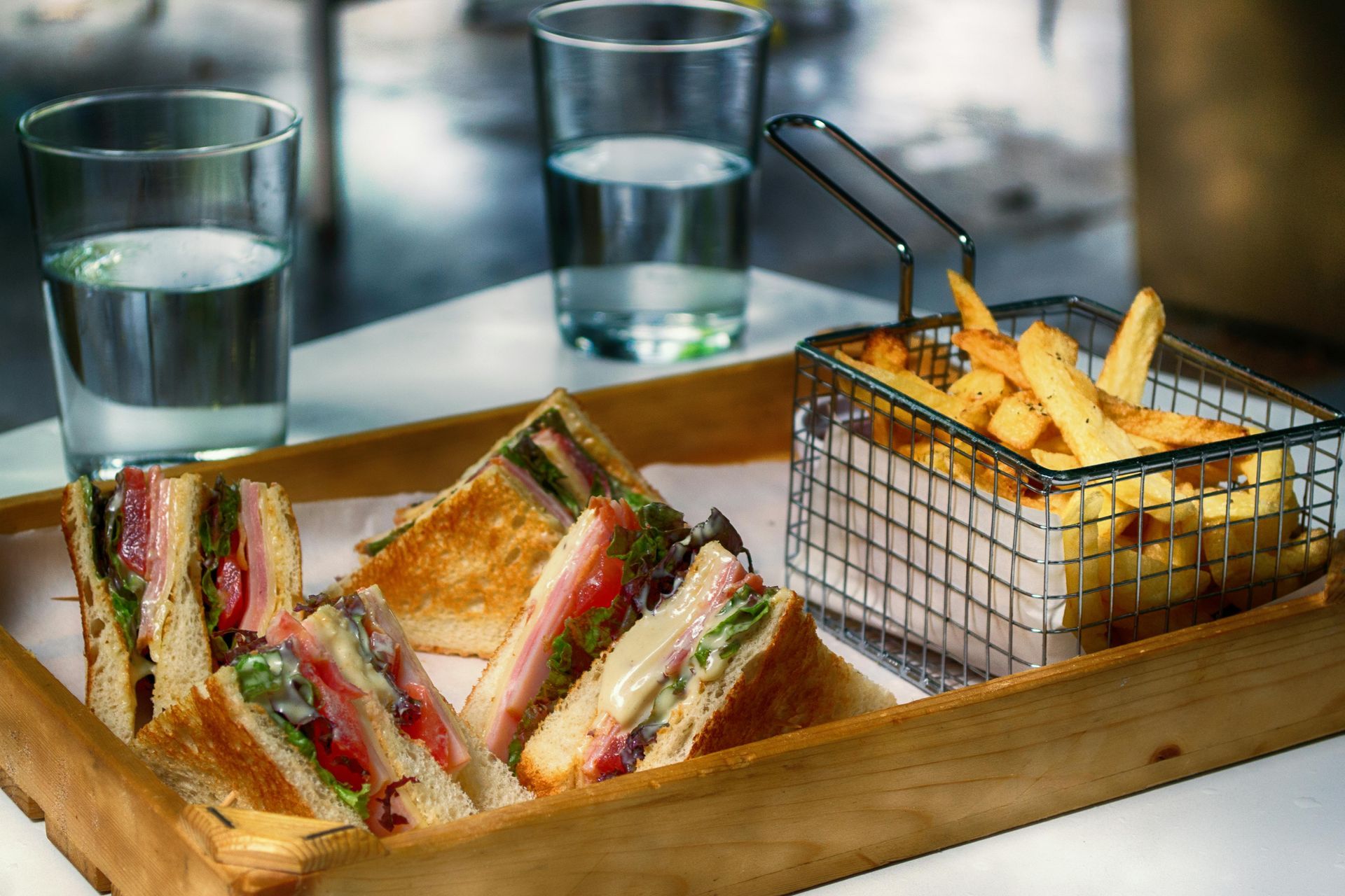 A wooden tray with sandwiches and french fries on it