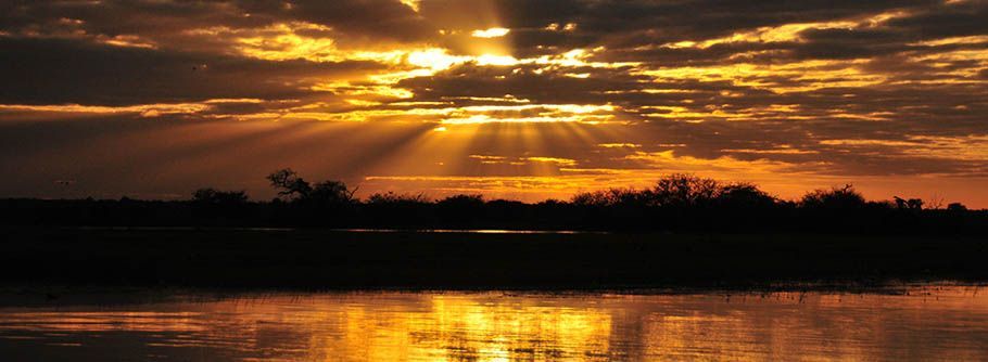 The sun is shining through the clouds over a lake.
