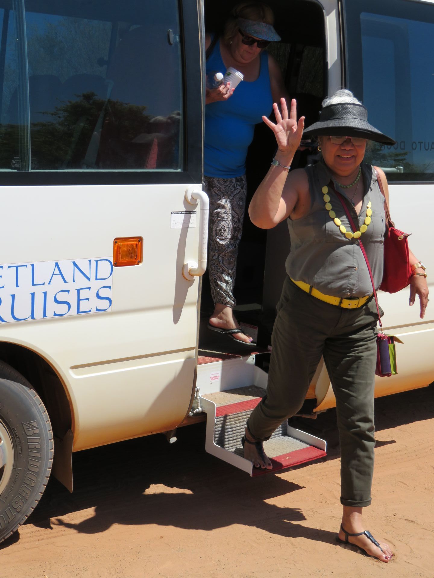 A woman is standing in front of a bus that says ' outland cruises ' on the side