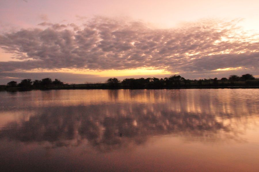 A sunset over a lake with trees in the background
