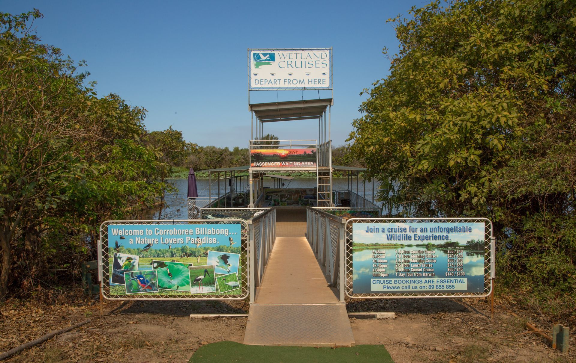 A bridge leading to a tower overlooking a body of water surrounded by trees.