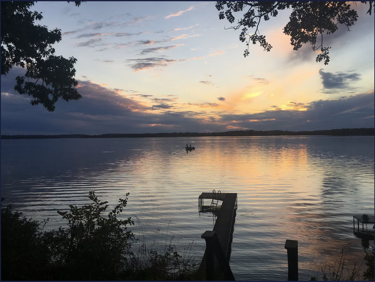 A sunset over a lake with a dock in the foreground
