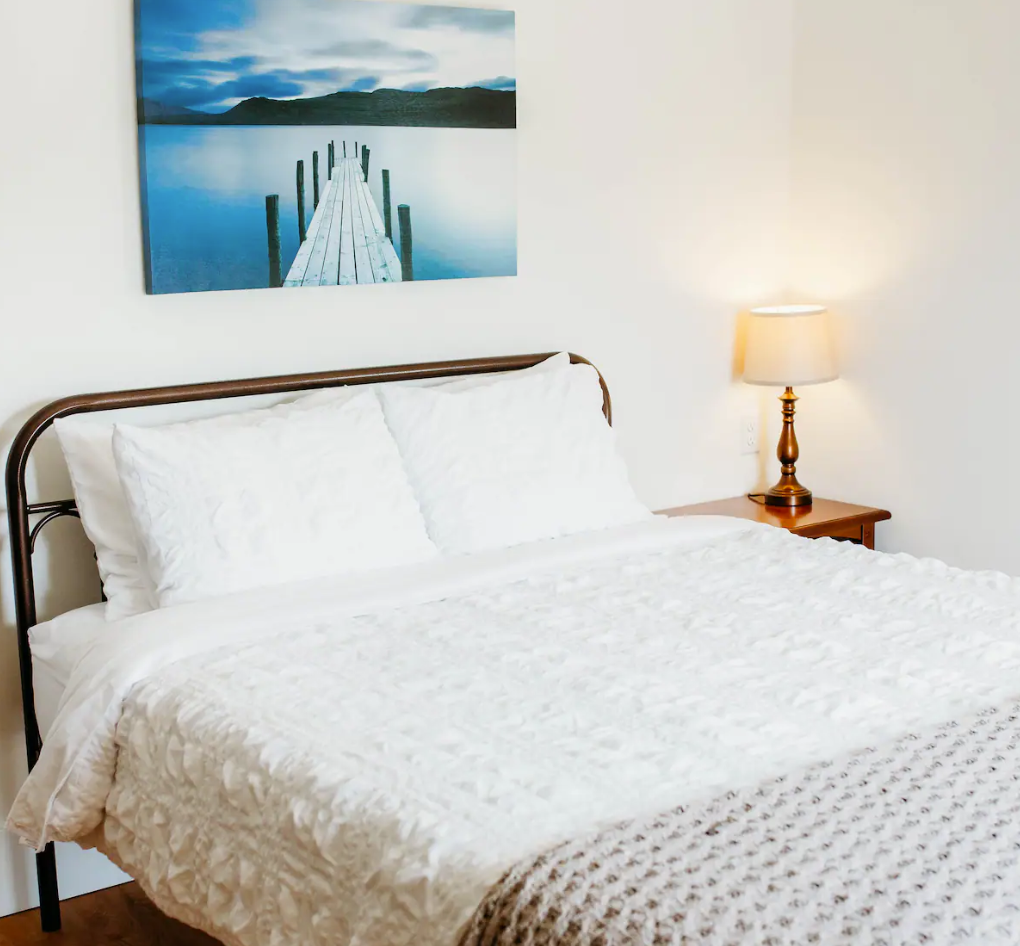 A bed in a bedroom with a painting on the wall above it