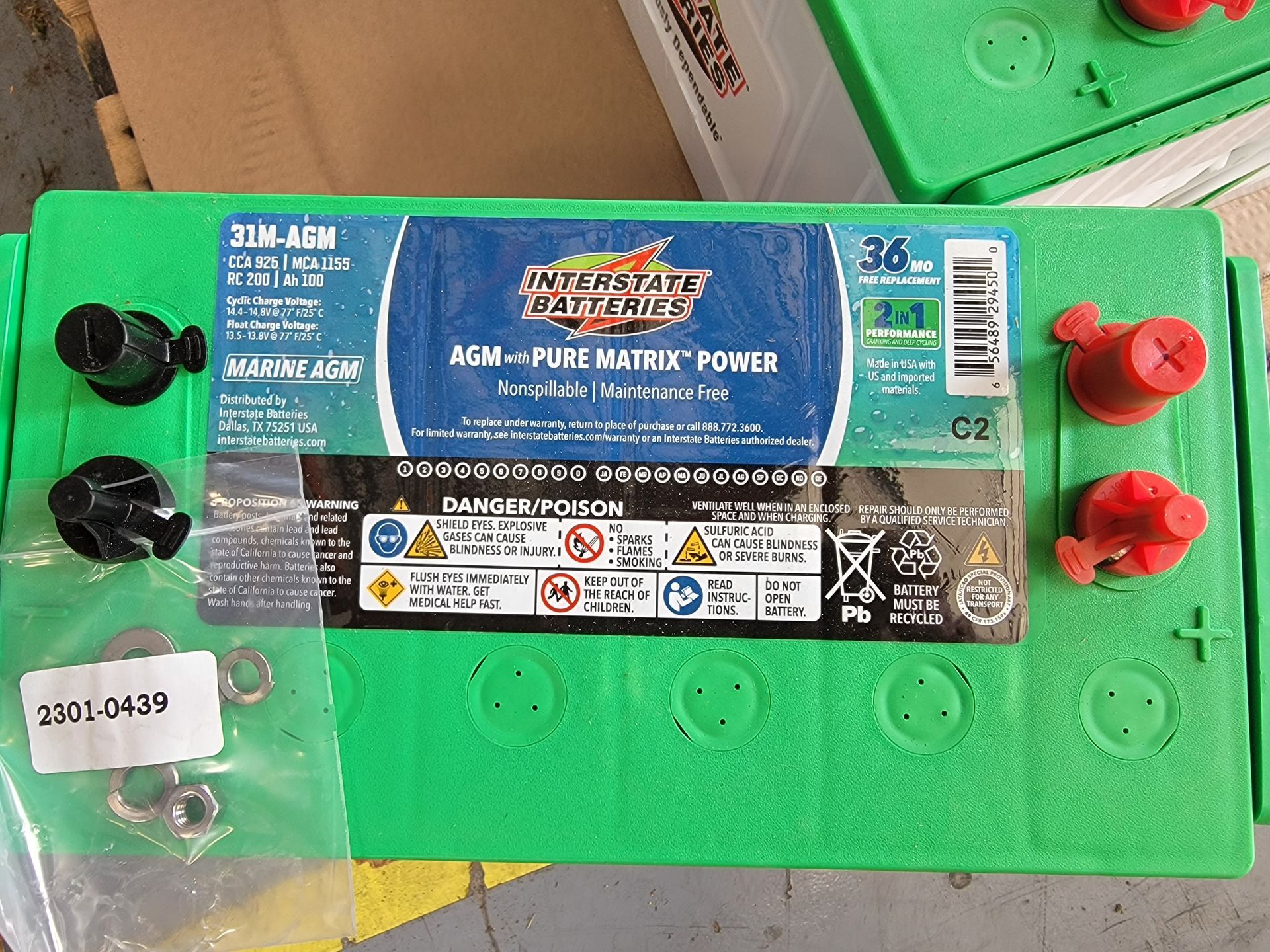 Green Interstate battery with terminals, caps, and mounting hardware on a surface.