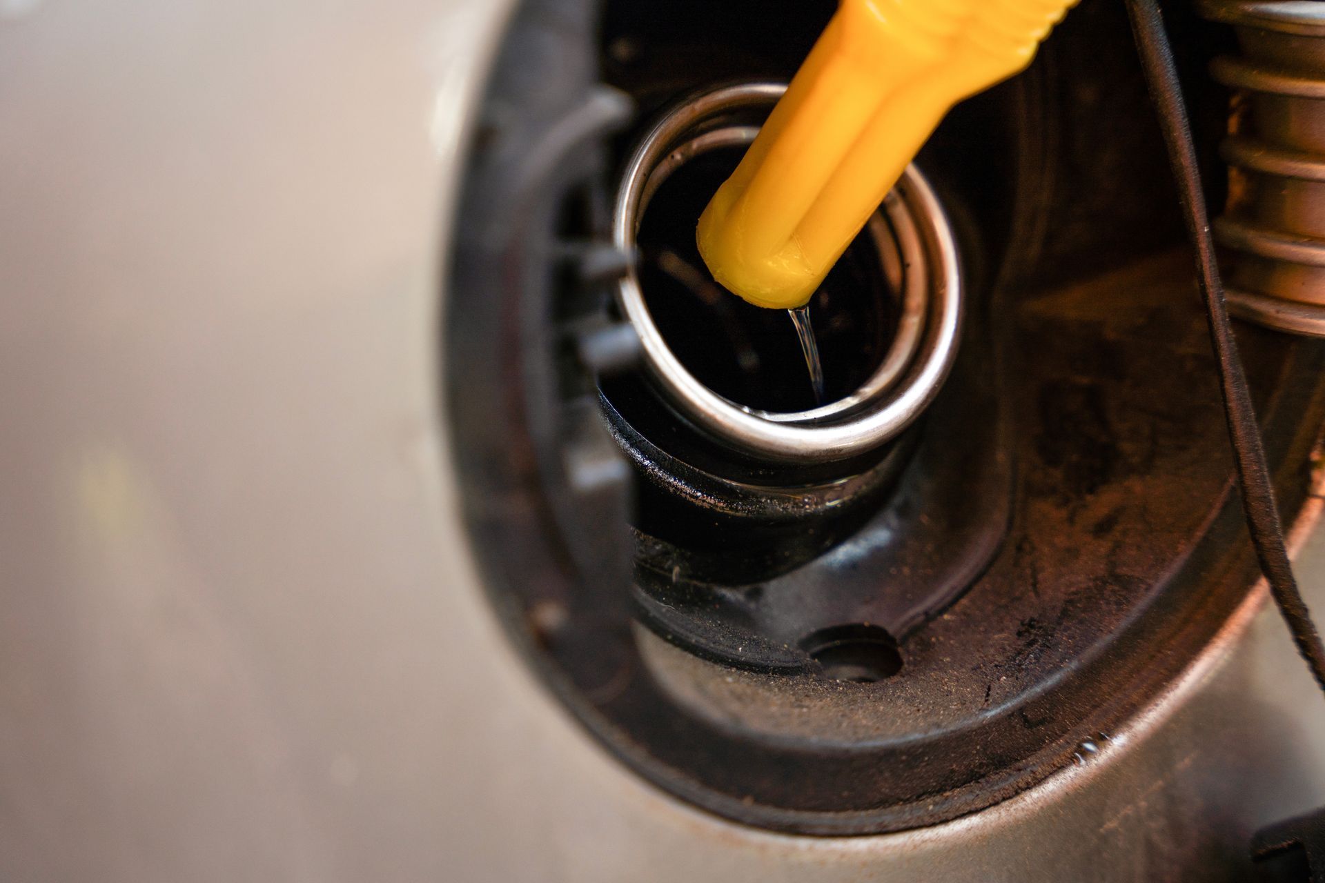 Yellow fuel nozzle filling car's gas tank; close-up.