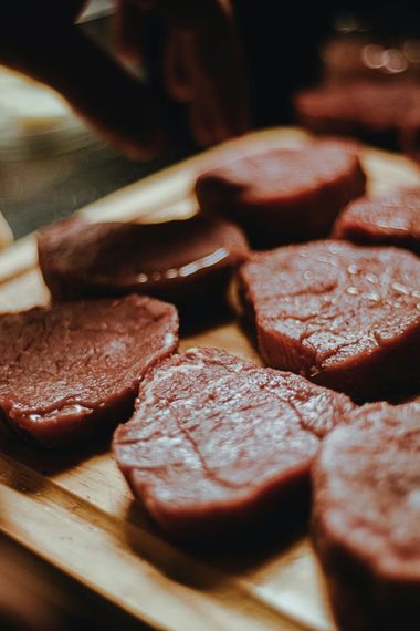 Three thick, raw steaks with high-quality marbling arranged on a wooden cutting board.
