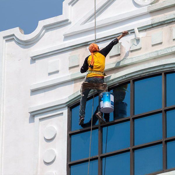 Man Painting Building Exterior — About Us in Bundaberg, QLD