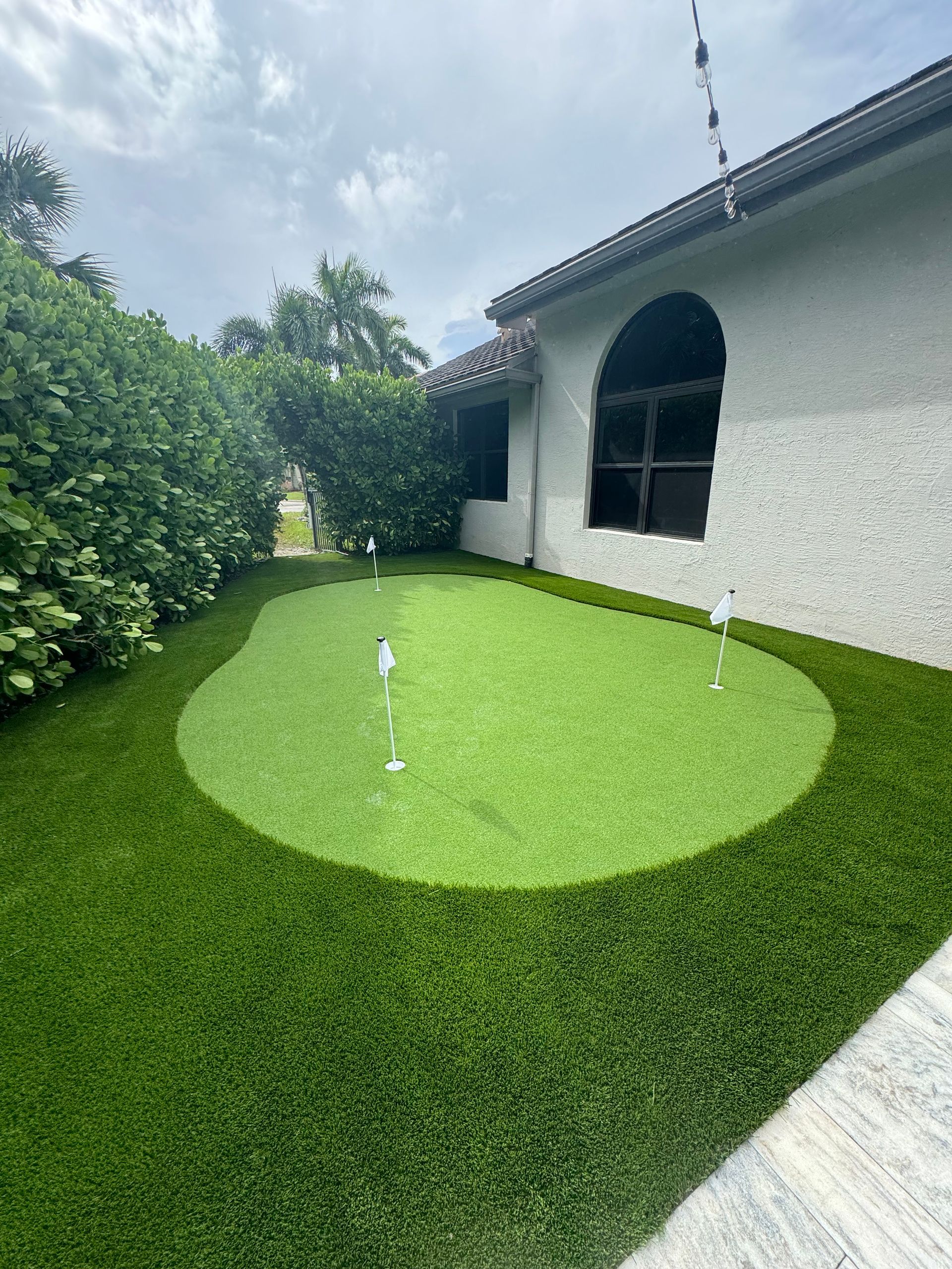 There is a putting green in the backyard of a house.