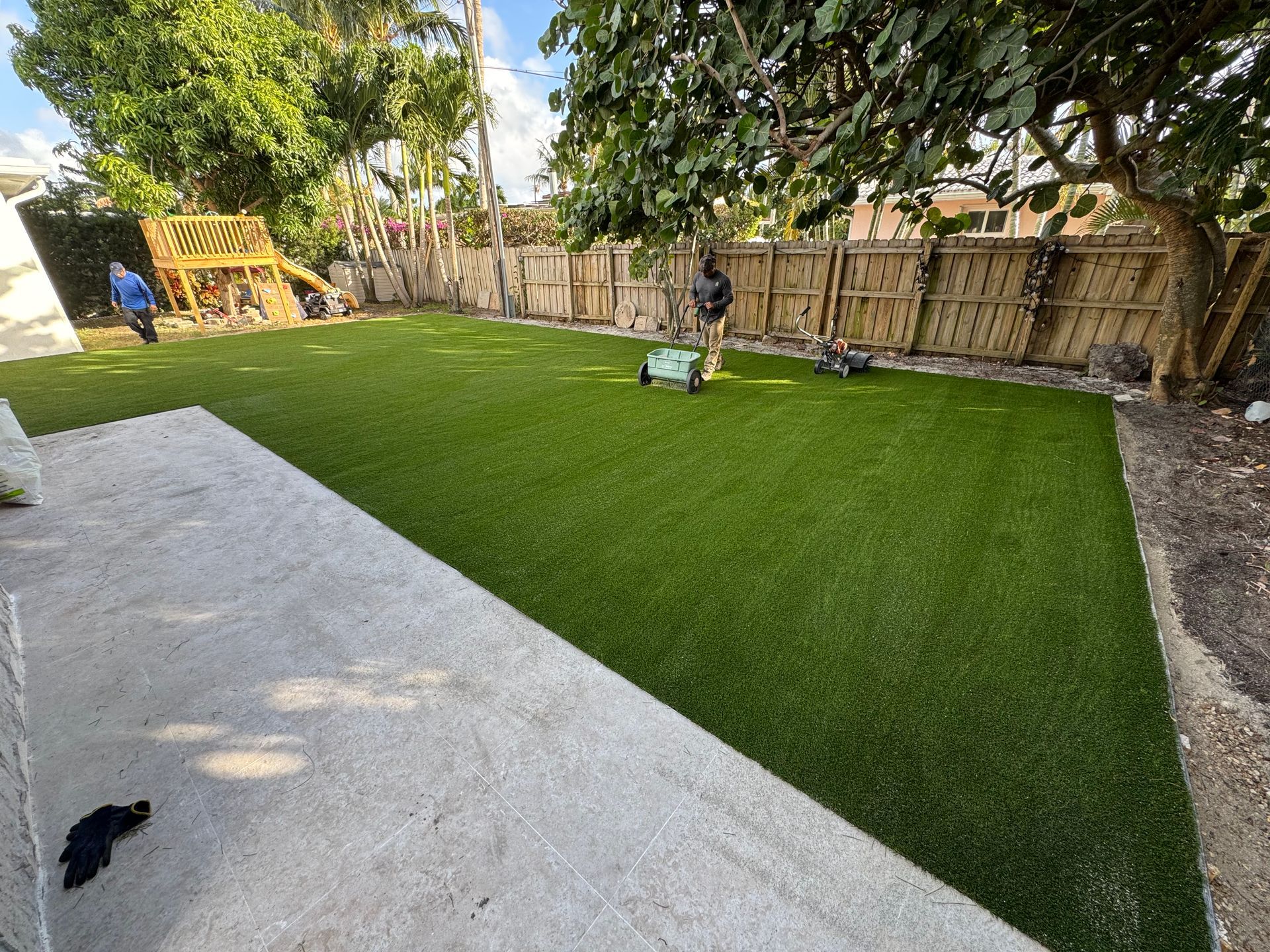A man is cutting grass in a backyard with a lawn mower.
