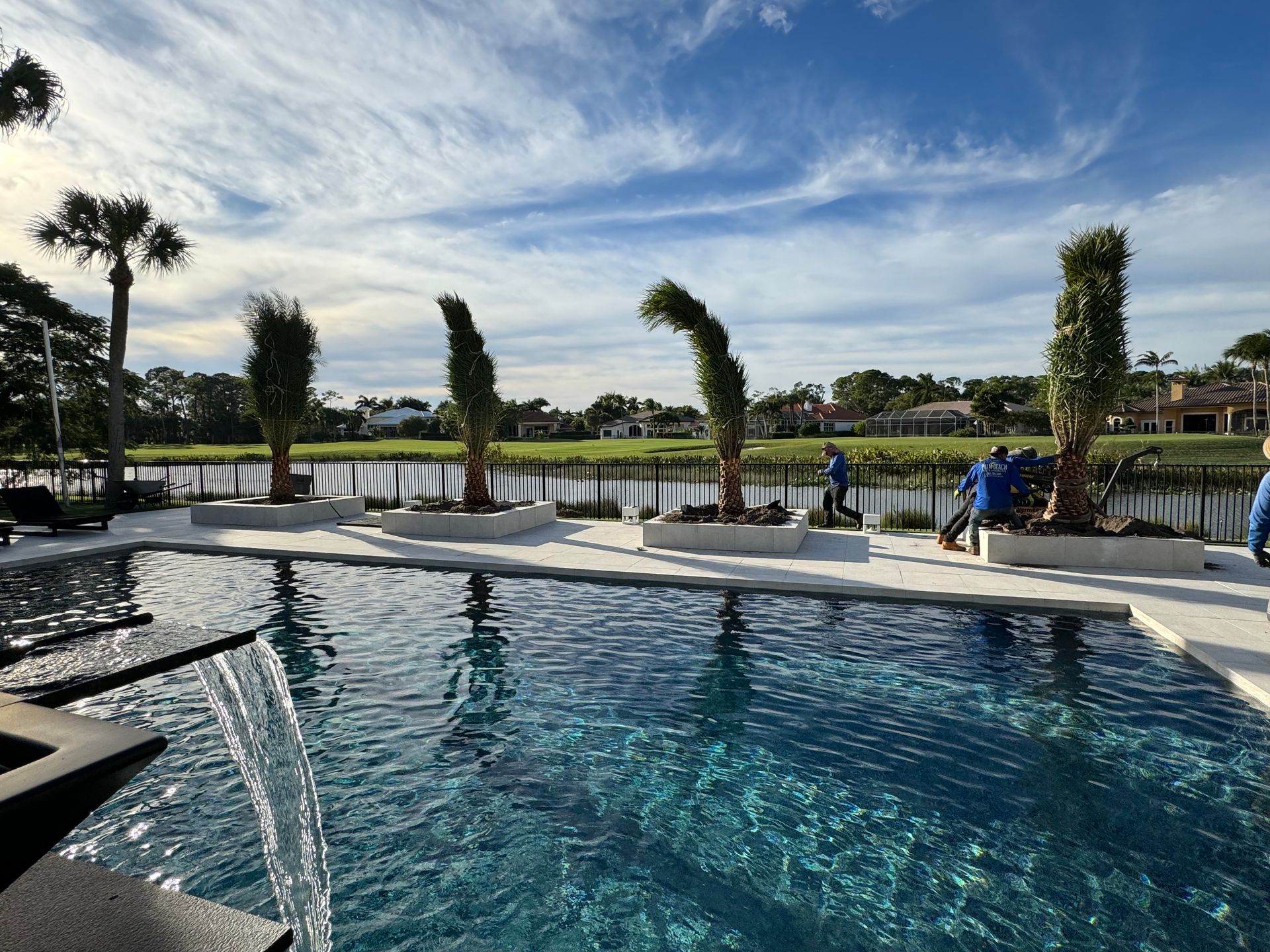 A large swimming pool with a waterfall and palm trees in the background