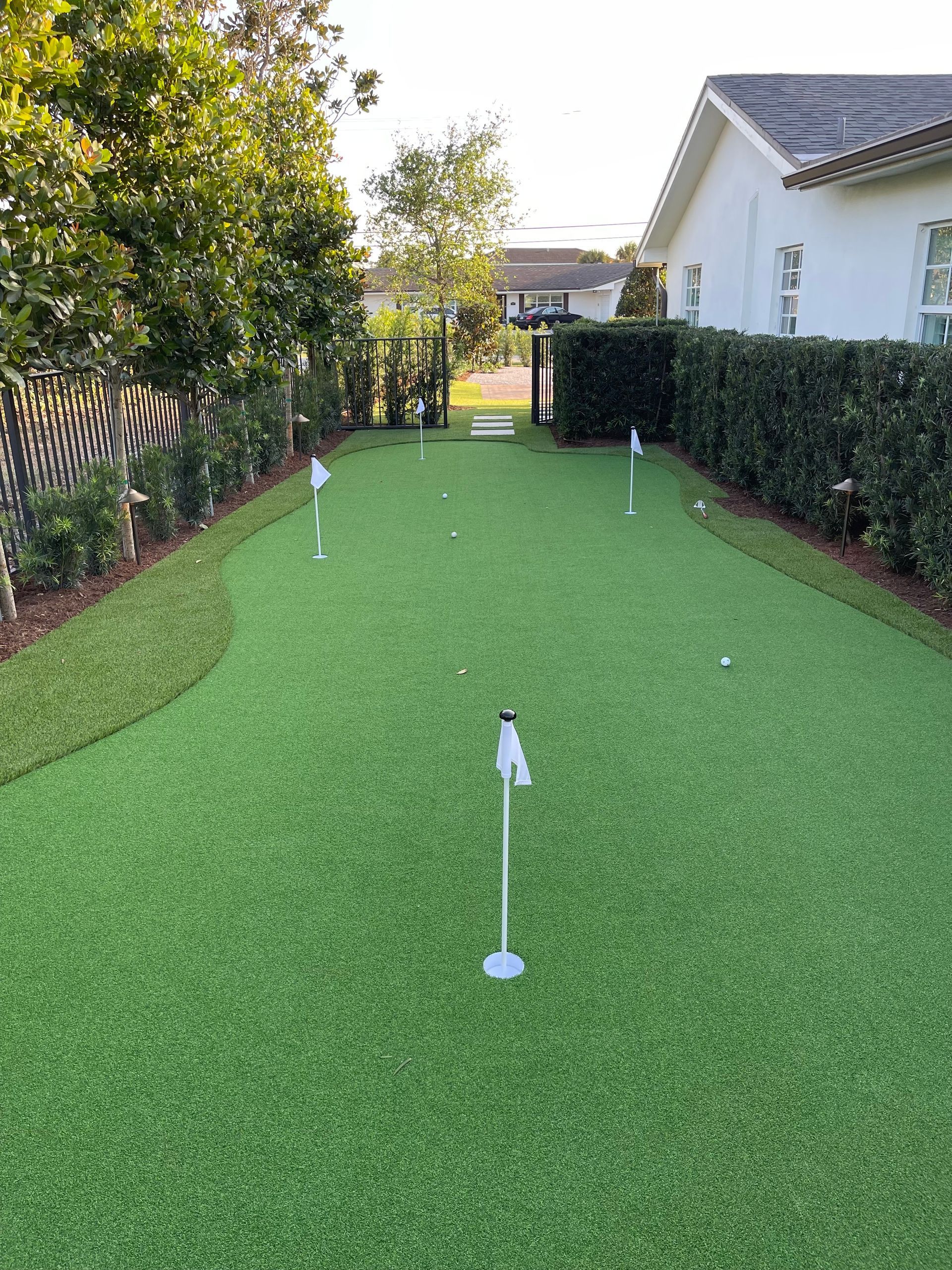 There is a putting green in the backyard of a house.