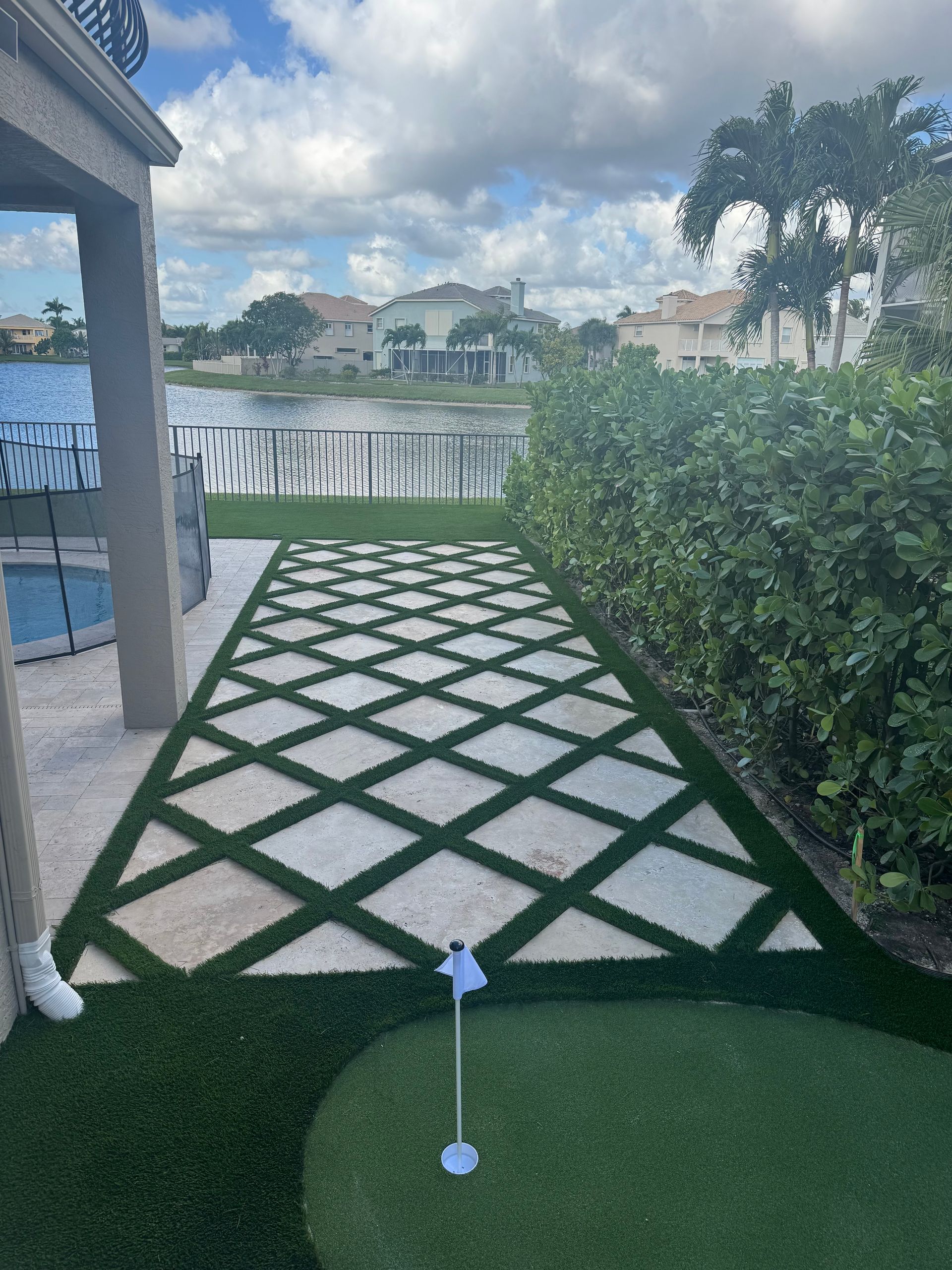 A putting green in a backyard next to a pool.