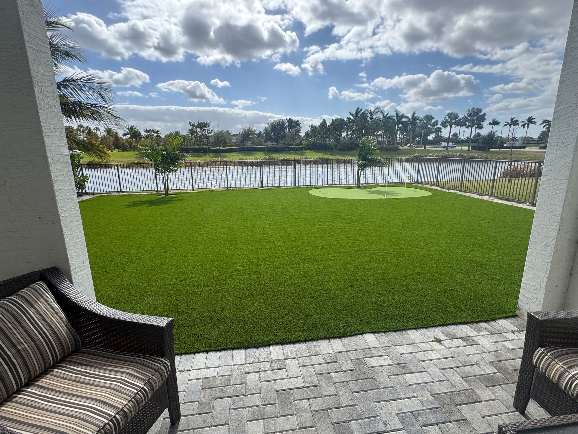 A patio with a couch and chairs overlooking a lush green lawn.