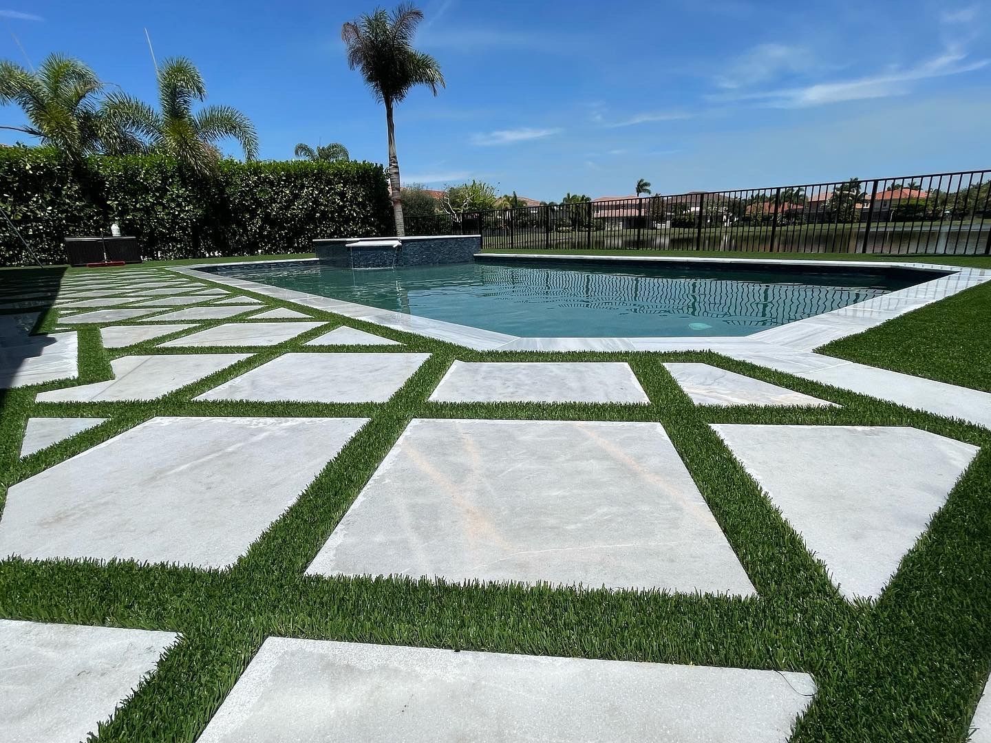 A swimming pool is surrounded by a lush green lawn.