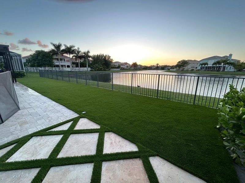 A lawn with a fence and a lake in the background.