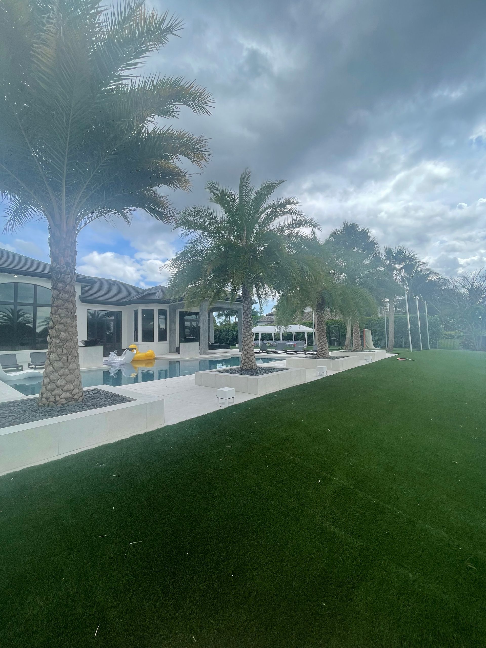 A large house with a lush green lawn and palm trees in front of it.