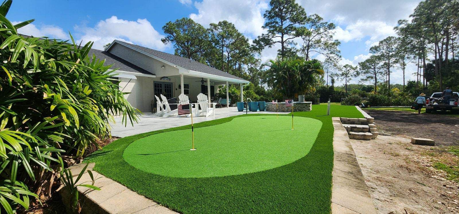 There is a putting green in the backyard of a house.
